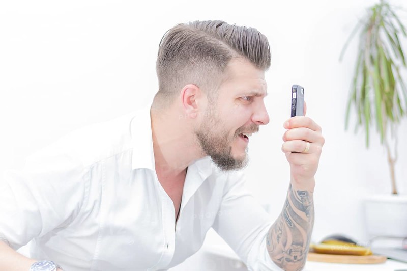 Man in a shirt looks at the smartphone screen in surprise. Concept of unsuccessful betting on games