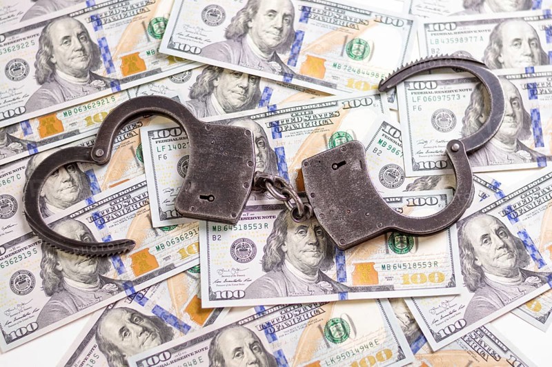 Handcuffs on the background of hundred-dollar bills. Illegal trade. Justice concept.