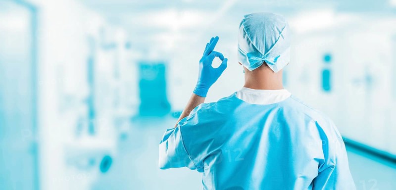 Portrait of a doctor in a clinic. He shows an ok sign. The view from the back. Medicine concept.