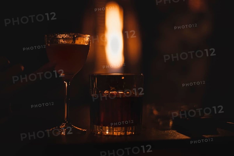 Image of a glass with a cocktail in a night bar against the background of a fiery heater. Restaurant concept