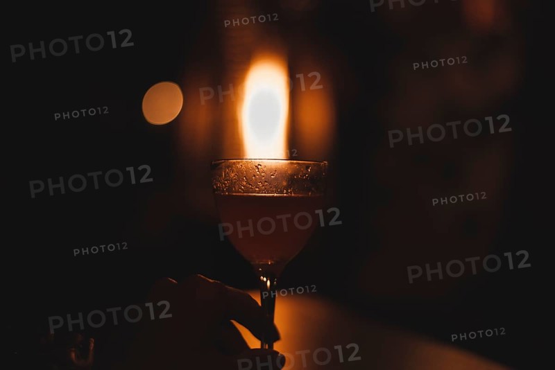 Image of a glass with a cocktail in a night bar against the background of a fiery heater. Restaurant concept
