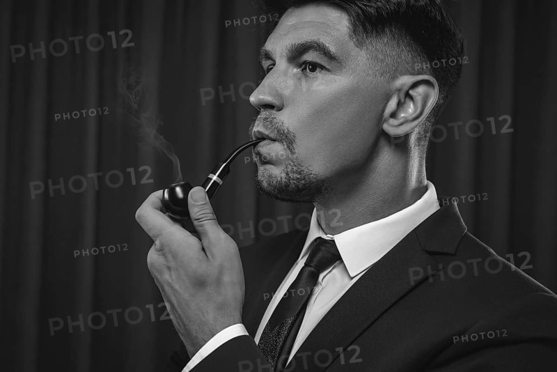 Image of an elegant man in a suit smoking a pipe. Business success concept.
