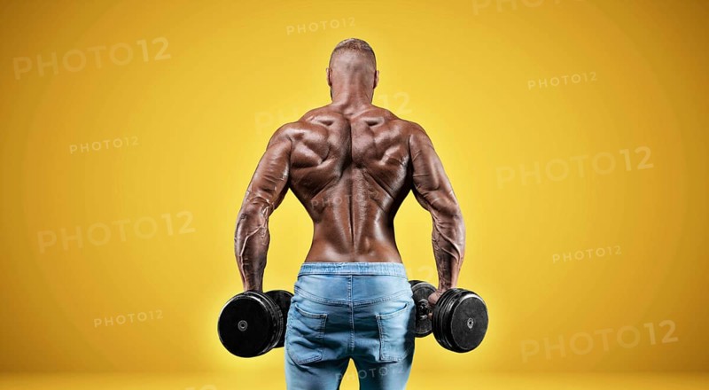 Isolated professional sportsman on a yellow background. Bodybuilding concept. Panorama. Advertising of a gym and sports nutrition.
