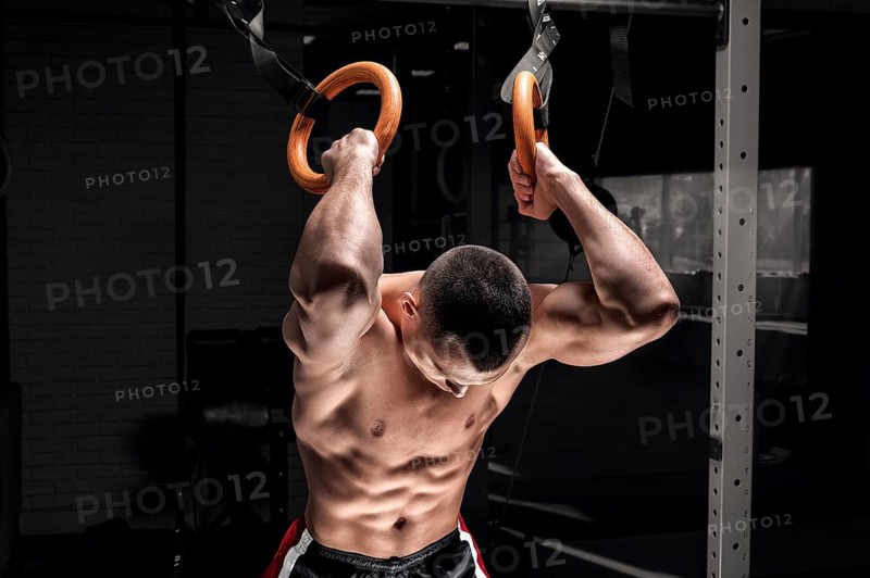 Athlete does warm-up on gymnastic rings. The concept of sport and healthy lifestyle.