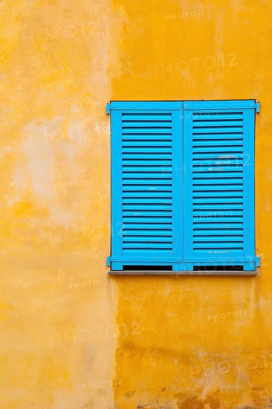Blue shutter on yellow plaster wall