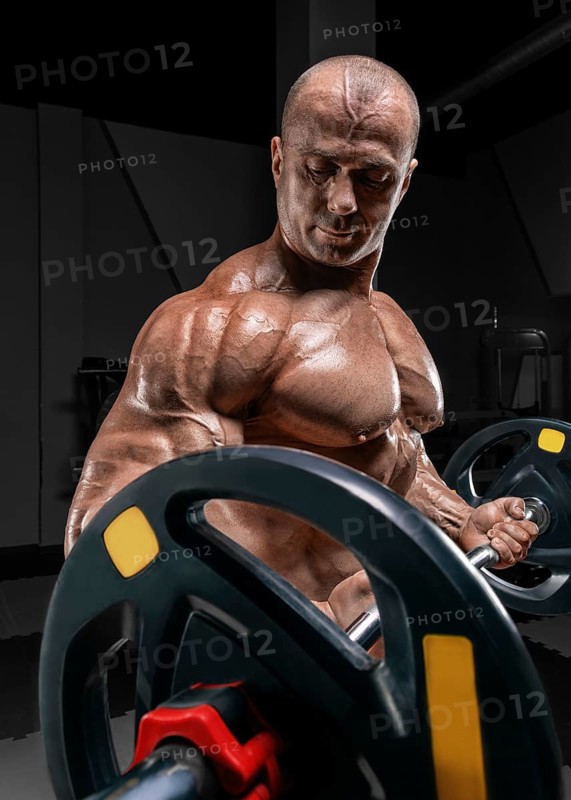 Professional weightlifter posing in the gym with a barbell in his hands. Classic bodybuilding.