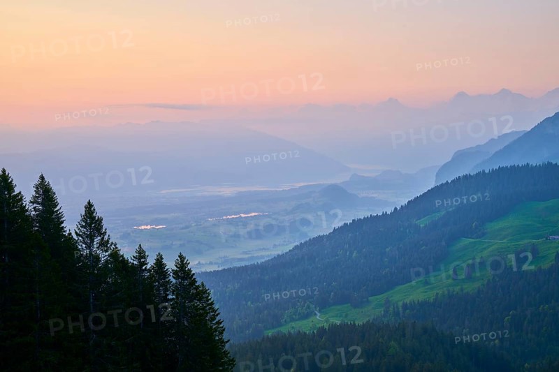 Sunrise over a misty mountain landscape with forest in the foreground