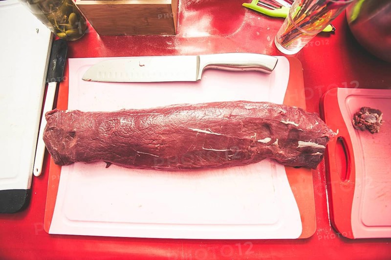 A piece of meat is marinated and prepared for grilling
