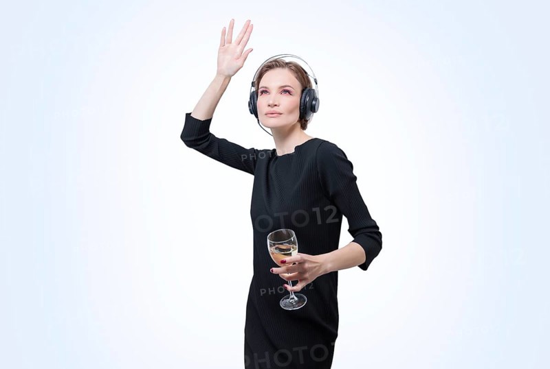 Portrait of a woman in professional headphones with a glass of wine in her hand. White background. Dj concept.