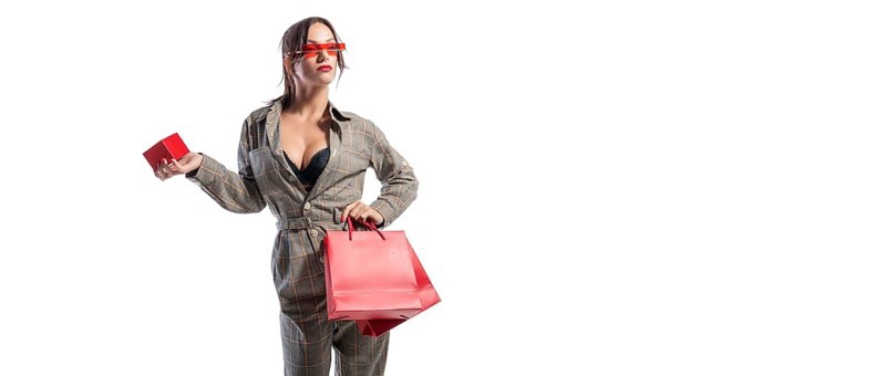 Charming brunette in glasses posing in the studio with red bags and a box for jewelry. White background. Shopping concept.