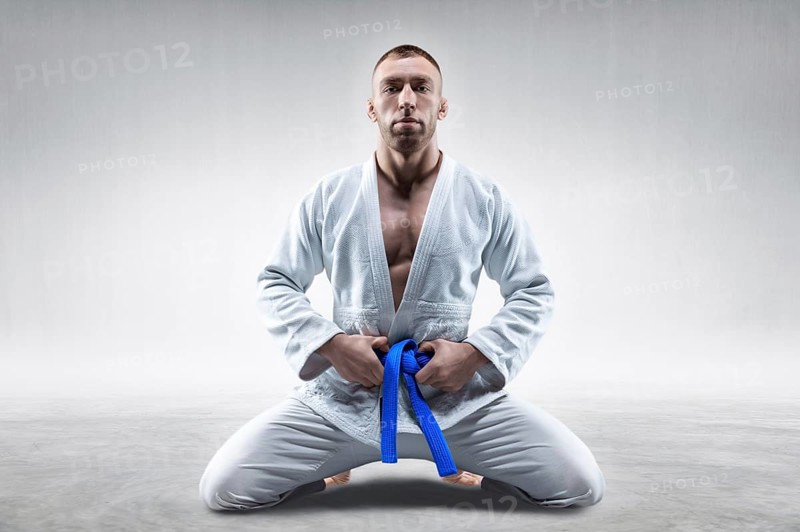 Athlete in a kimono with a blue belt sits and waits for the opponent. Concept of karate