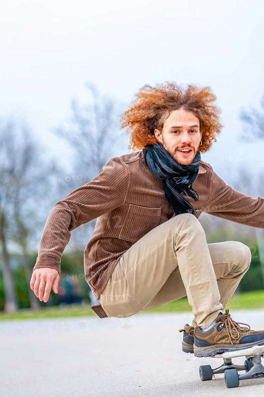 Vertical photo with copy space of a happy young man skateboarding in a park
