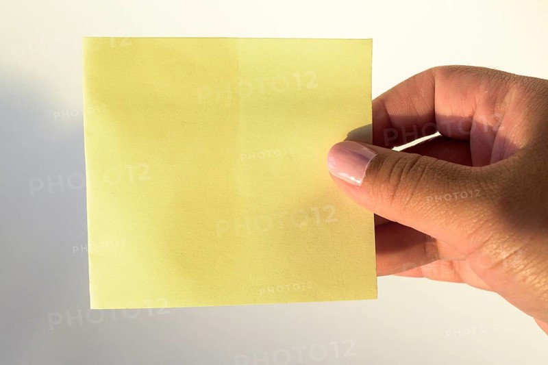 Woman's hand with painted nails holding blank letter paper on pure white background