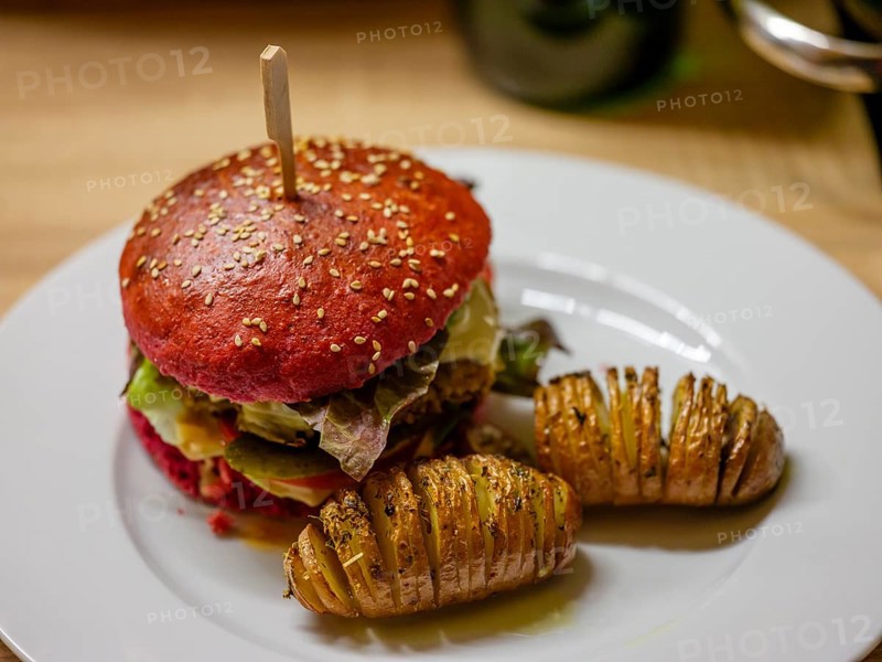 Delicious veggie burger in a beetroot bun with sliced potatoes
