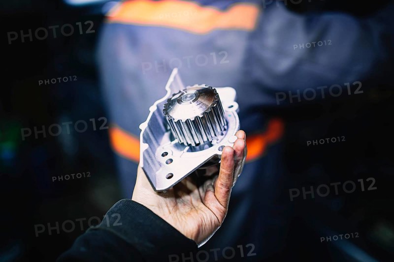 Automotive water pump of the engine cooling system in the hands of an auto mechanic