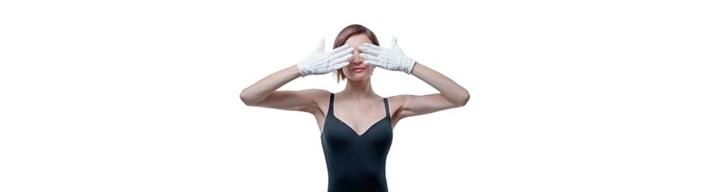 Beautiful young woman in white gloves covered her eyes with her hands