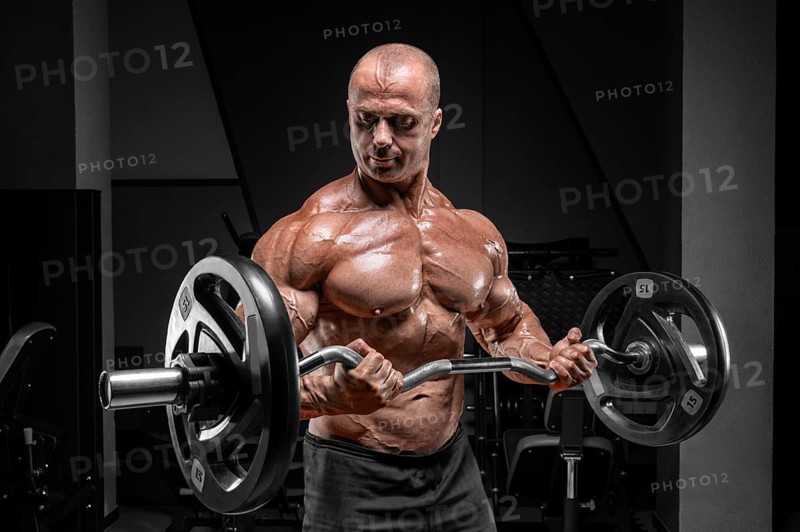 Professional weightlifter posing in the gym with a barbell in his hands. Classic bodybuilding.