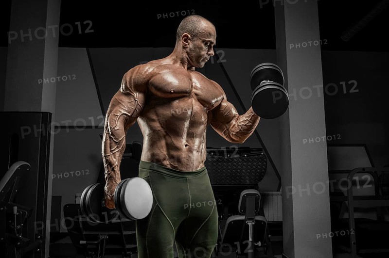Professional weightlifter is training in the gym. Dumbbell Curl. Bodybuilding concept.