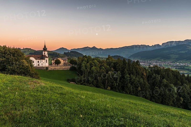 Church in the hamlet of Schlatt with a view of the Alpstein mountains with Hoher Kasten and the village of Appenzell at dusk