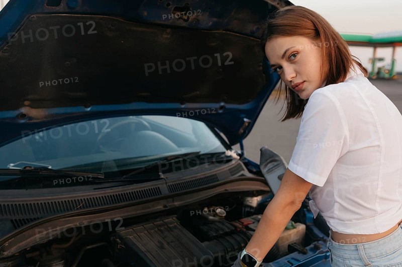 Young beautiful hot girl auto mechanic pours oil