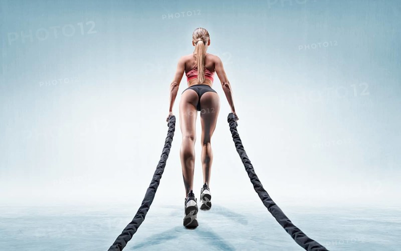 Sports girl trains with ropes. Back view. The concept of sports