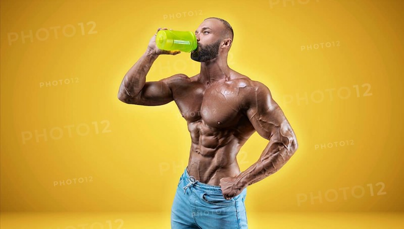 Isolated professional sportsman on a yellow background. Bodybuilding concept. Panorama. Advertising of a gym and sports nutrition.