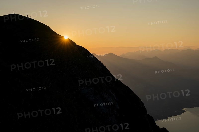 Mountain ridge with mountaineers and Swiss mountains and Lake Thun in the background at sunrise