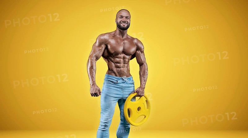 Isolated professional sportsman on a yellow background. Bodybuilding concept. Panorama. Advertising of a gym and sports nutrition.
