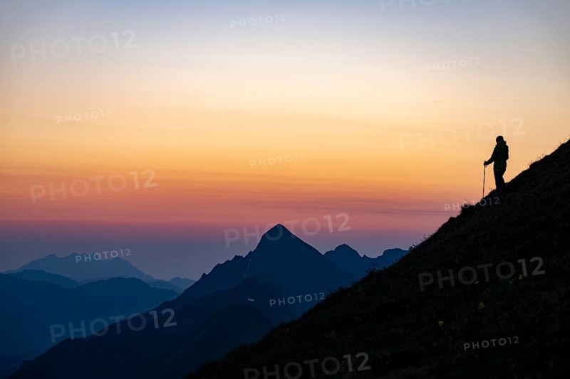 Mountaineer on mountain ridge with Rothorn peak in the background at blue hour