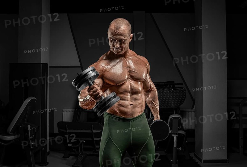 Professional weightlifter is training in the gym. Dumbbell Curl. Bodybuilding concept.