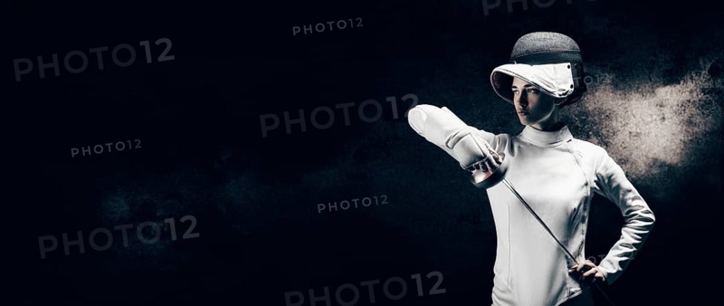 Charming girl dressed as a fencer posing with a mask and a sword. The concept of fencing.