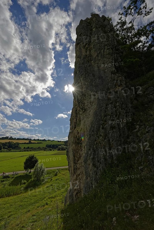 Striking limestone rock formation Burgstein with blue and white sky in the upper Altmuehltal surrounded by green vegetation