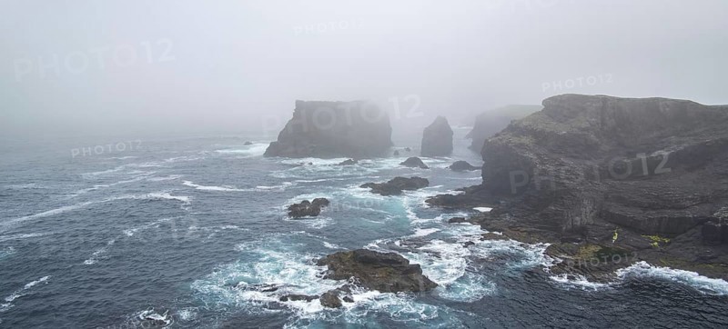 Sea stacks and sea cliffs in mist during stormy weather at Eshaness