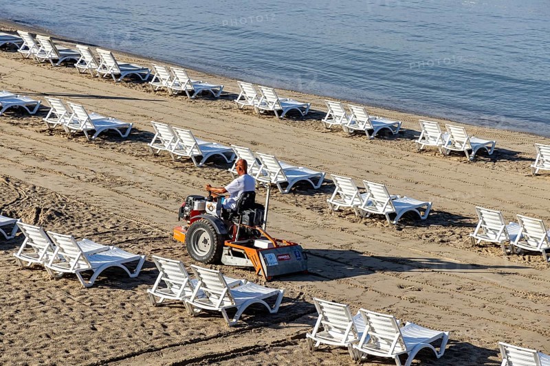 Early in the morning on the sandy beach of Kusadasi. The sunbeds are being prepared