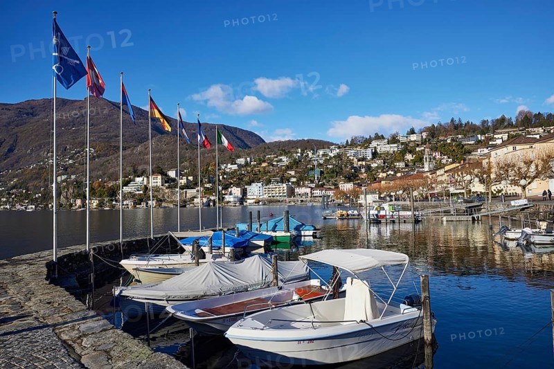 Motorboats and stone wall with flags in the harbour of Ascona