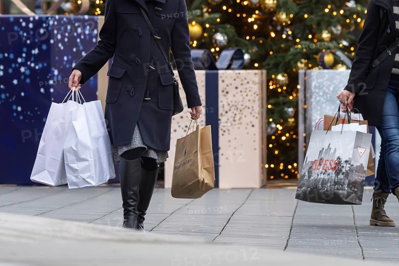 Christmas shopping at Outletcity Metzingen. Consumer tourists lug shopping bags. Factory outlet with around 80 shops of premium and luxury brands specialising in clothing
