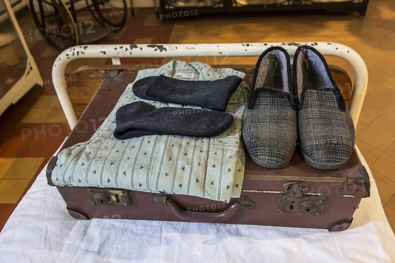 Suitcase with pyjamas and slippers of psychiatric patient on hospital bed in the Dr Guislain Museum about the history of psychiatry in the former Guislain Hospice