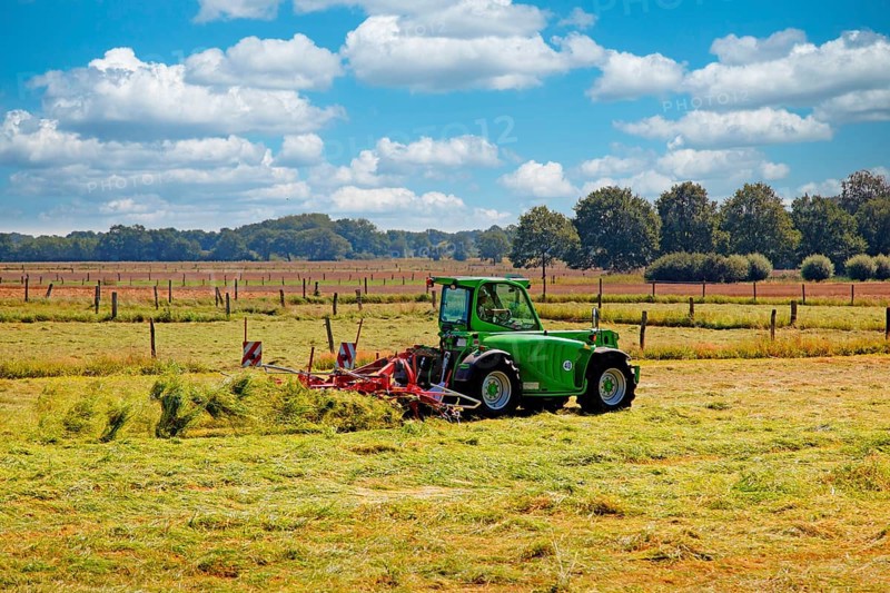 A farmer with his tractor and hay tedder