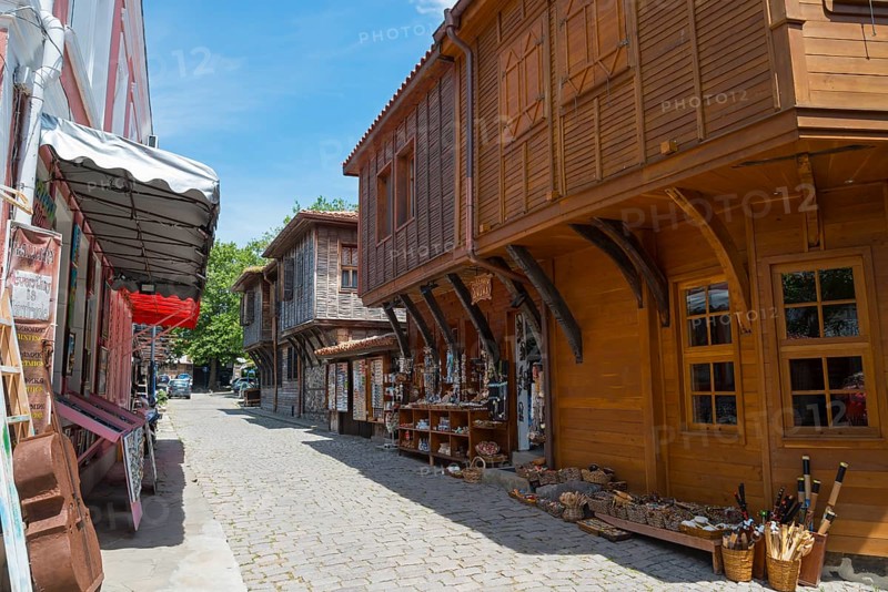 Cobbled street surrounded by shops with traditional wooden facades under a clear blue sky