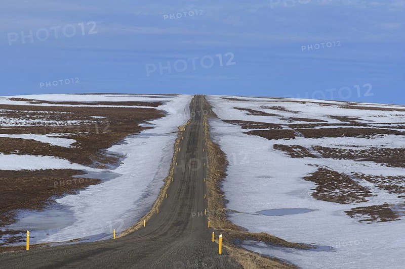 Road leading through the tundra towards the mountain range Lambafjoell