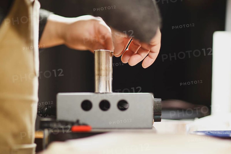 Unrecognizable luthier lute maker artisan both hands performing bend controller purfling strips process in iron tool for a new raw back and front plates of classic handmade violin in his workshop in Cremona