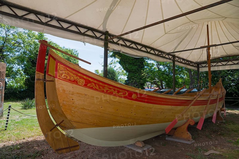Traditional wooden boat under a white tent on a sunny day with green surroundings
