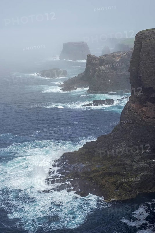 Sea stacks and sea cliffs in mist during stormy weather at Eshaness
