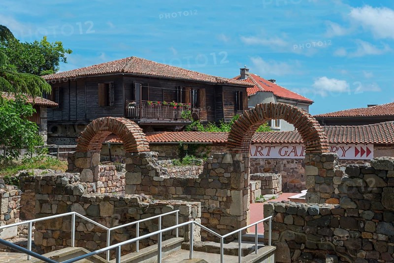 View of a traditional house behind old brick arches under a sunny sky