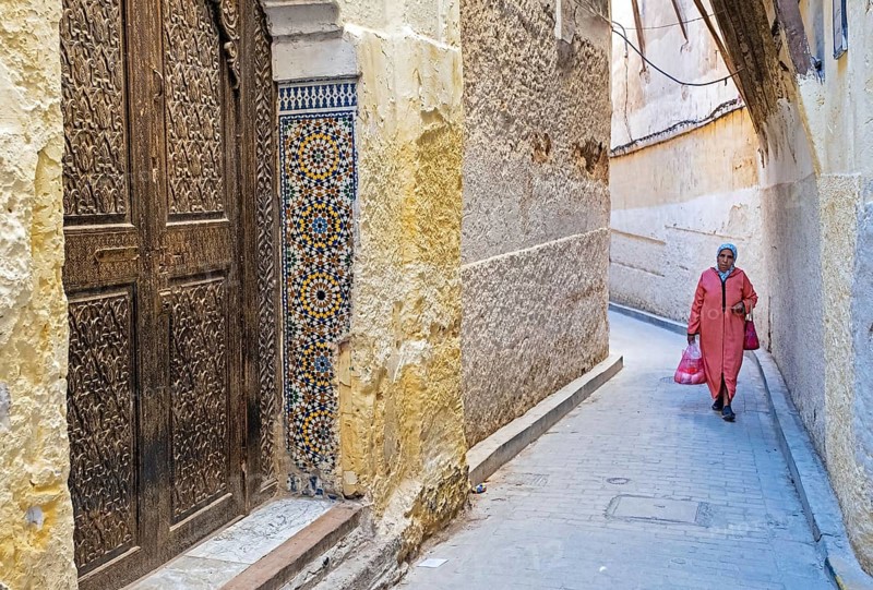 Beautiful carved wooden door and Muslim woman wearing djellaba