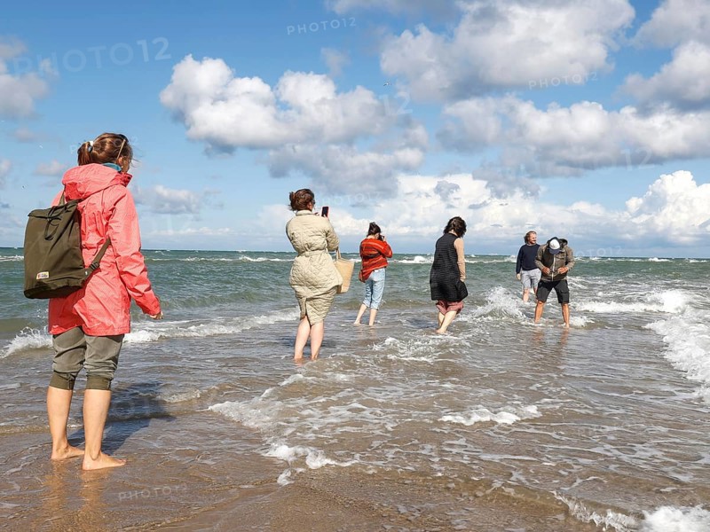 Tourists stand with one foot in the North Sea and one in the Baltic Sea in Grenen or Skagens Gren