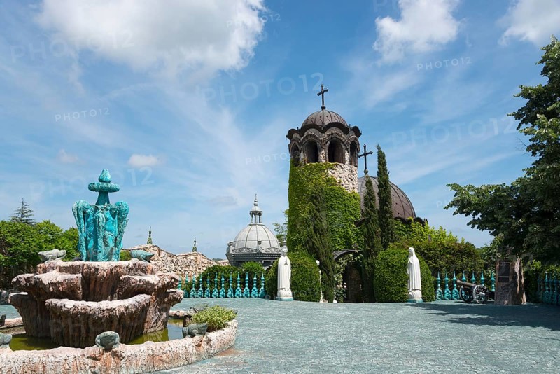 A chapel with religious statues and water basins surrounded by inviting greenery
