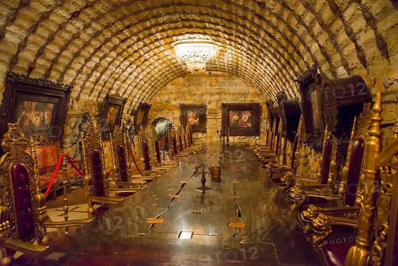 Historic interior with vaulted stone ceiling and ornate chairs under warm light