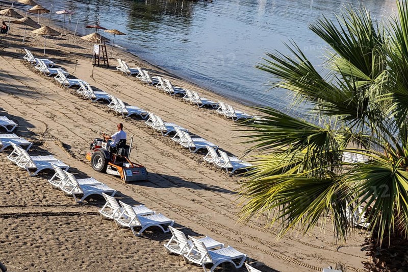 Early in the morning on the sandy beach of Kusadasi. The sunbeds are being prepared