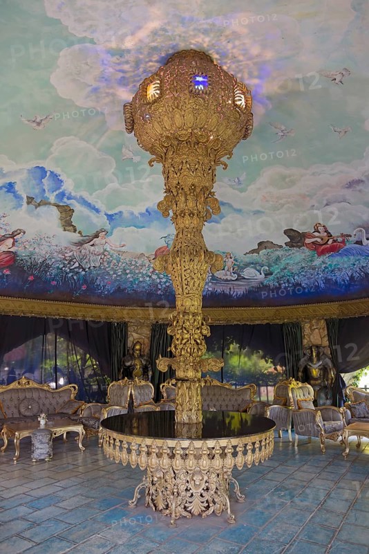 Magnificent interior with a large chandelier surrounded by painted angels and a blue sky as well as luxurious furniture